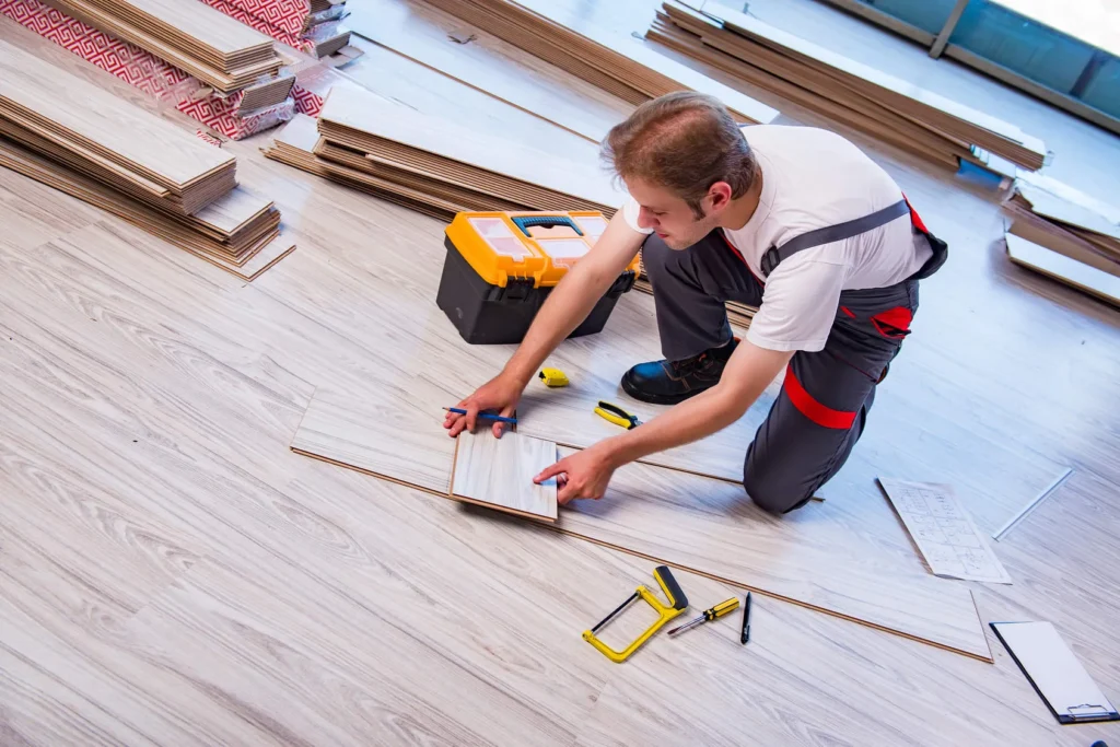 Technician performing flooring repair and installation with tools and wood panels